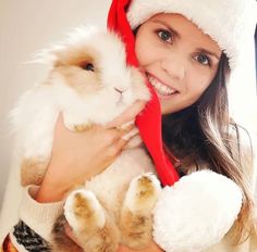 a woman in a santa hat holding a rabbit