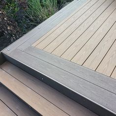 a close up of a wooden deck with grass in the background