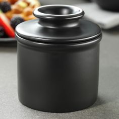 a black canister sitting on top of a table next to a plate of food