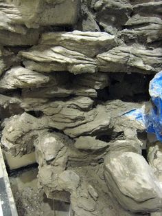 there are many large rocks that have been dug into the ground by people with blue tarps on them