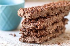 three chocolate oatmeal cookies stacked on top of each other next to a blue cup