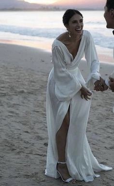 a man and woman holding hands on the beach