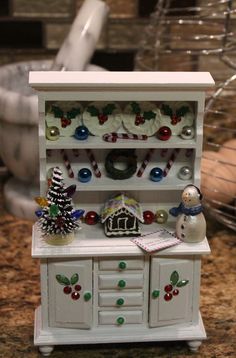 a miniature christmas hutch with ornaments and decorations