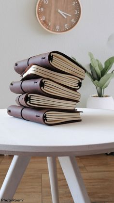 a stack of books sitting on top of a white table next to a wall clock