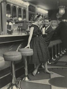 an old black and white photo of a man and woman at a bar with their arms around each other