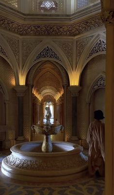 a large fountain in the middle of a room with arches and columns on either side