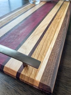 a wooden cutting board with a knife sticking out of it's center piece on a table