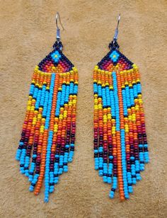 two pairs of colorful beaded earrings sitting on top of a brown carpeted floor