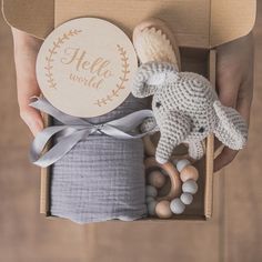 a person holding an elephant toy in a box with it's lid open to reveal its contents