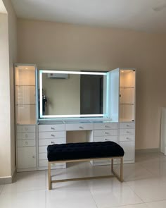 an empty room with a large mirror and white drawers on the wall next to a bench