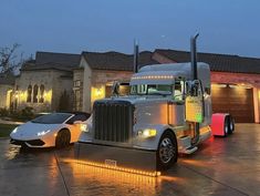 a white car and a silver truck parked in front of a house with lights on