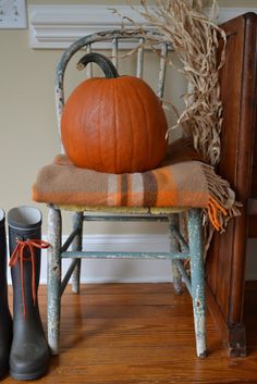 a wooden chair with a pumpkin on top of it next to a pair of boots