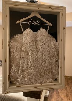 a dress hanging in a frame with the word bride on it