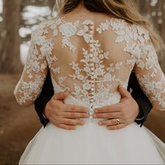 the back of a bride's dress as she walks through the woods with her groom