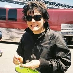 a young man holding a green frisbee in front of a train