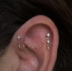 a woman's ear is adorned with gold and diamond stars, which are attached to the side of her ear