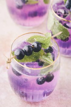 a glass filled with blueberries and mint garnish on top of a table