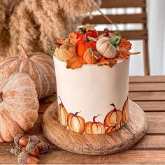 a decorated cake sitting on top of a wooden table next to pumpkins and gourds