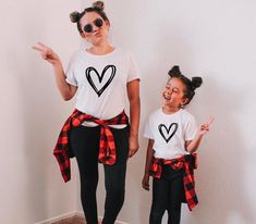 model matching with daughter wearing black hollow heart vinyl print on a white t shirt. mother and daughter with pigtail buns  making silly faces at the camera . both model and mini model dressed up t shirt wearing matching black pants and a red and black checker flannel around the waist. Mommy And Me Christmas Outfits, Mommy And Me Christmas Shirts, Mama And Mini Shirts, Mommy And Me Christmas, Mini Shirts, Mama And Mini, Mommy And Me Shirt, Look Short, Mommy And Me Outfits