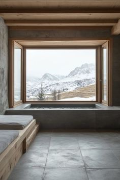 a room with two beds and a large window overlooking the snow covered mountain range in the distance