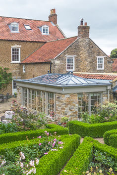 a house with a garden in front of it that has hedges growing on the sides