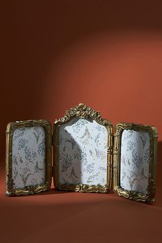 three ornate frames sitting next to each other on a red surface with an orange wall in the background