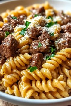 a close up of a bowl of pasta with meat and parmesan cheese on top