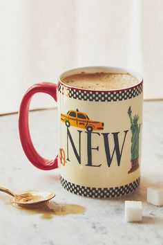 a coffee mug with the word new on it next to some sugar cubes and a spoon