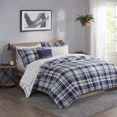 a bed with blue and white plaid comforter in a room next to a window