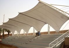 a man is sitting on the bleachers under an awning