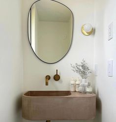 a bathroom sink sitting under a round mirror next to a wall mounted faucet