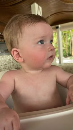 a baby sitting in a high chair looking at something