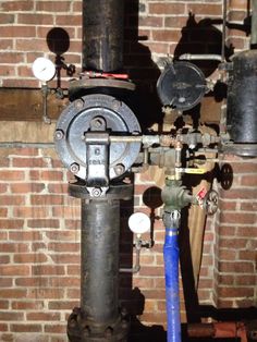 pipes and valves are attached to a brick wall