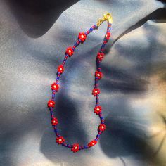 Red/Blue daisy chain necklace with gold clasp. **Bracelet sold separately** Trendy Red Beaded Choker Necklace, Trendy Red Round Bead Necklaces, Trendy Red Necklaces With Round Beads, Trendy Red Round Beads Necklace, Trendy Red Beaded Necklace With Beaded Chain, Trendy Red Beaded Chain Necklace, Trendy Handmade Red Beaded Necklaces, Red Adjustable Flower Necklace, Adjustable Red Flower Necklace