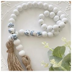 white beads and tassels are on a plate next to a potted plant