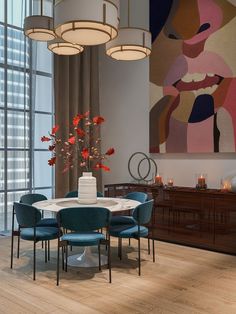 a dining room with blue chairs and a white table surrounded by art on the wall