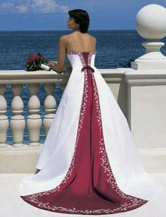 a woman in a white and blue wedding dress standing on a balcony overlooking the ocean