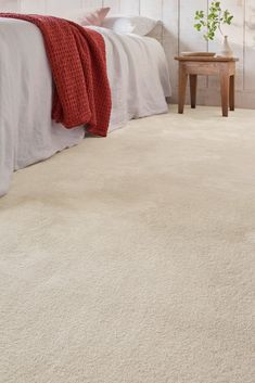 a white carpeted bedroom with a bed and nightstand