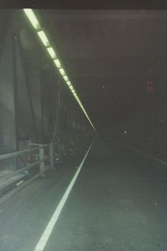 an empty tunnel with lights at the end and no people on it in the dark