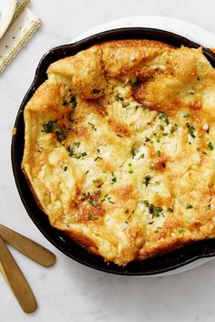 an omelet in a cast iron skillet on a white table with utensils