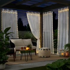 a living room with curtains and lights on the outside wall, in front of a patio