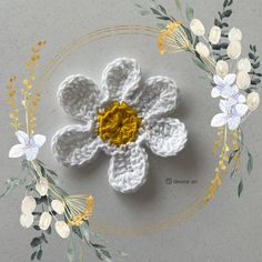 a crocheted flower with yellow center surrounded by white and yellow flowers on a gray surface