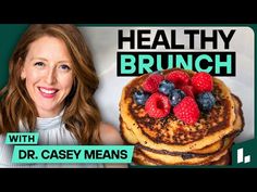 a woman smiling next to a stack of pancakes with berries on top