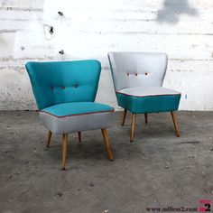 two chairs sitting next to each other in front of a white brick wall and cement floor