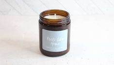 a candle is sitting on a table with a label that says feels like home in front of it