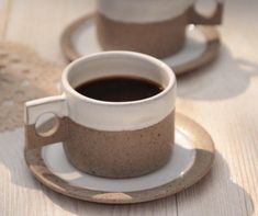 two coffee cups sitting on top of saucers