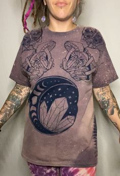 Made To Order  Custom Bleach Dye T Shirt that features a  crescent moon marked with the phases of the moon, crystals front and center accented by butterflies, mushrooms and crystals. On each side of the shirt displays a fern. The image seen is identical front and back.  I carry colors: Black or Navy, Sizes: Small- 4XL! Size chart shown in photos.  100% cotton, safe for fire flow artists. Bleach dyes t-shirts are all hand dyed by me. This is stock photo, due to the creative process of bleach dyei Mushroom And Crystal Shirt, Mystical Cotton Crew Neck T-shirt, Mystical Short Sleeve Top With Graphic Print, Mystical Graphic Print Short Sleeve Top, Mystical Graphic Print Crew Neck Top, Mystical Style Cotton T-shirt With Crew Neck, Mystical Crew Neck Cotton T-shirt, Mystical Style Cotton Crew Neck T-shirt, Graphic Tee With Moon Print For Festival