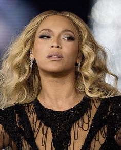 a close up of a woman with blonde hair and wearing a black dress at an event