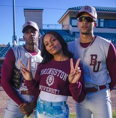 two baseball players and a woman standing in the outfield with their hands up to sign peace