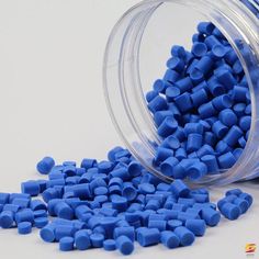 a jar filled with blue plastic pellets sitting on top of a table